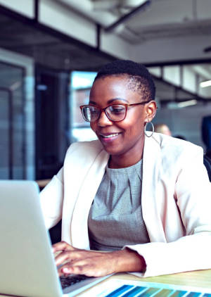 A person in business attire working at a notebook computer.