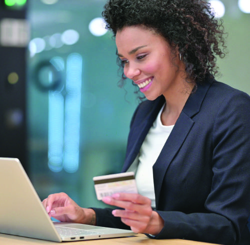 A woman holding a credit card while using a notebook computer